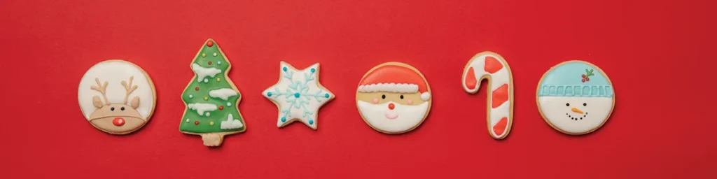 Galletas navideñas decoradas (reno, Papá Noel, árbol, muñeco de nieve) sobre fondo rojo — Dos Comas